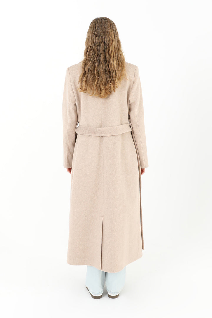 Woman wearing a long beige coat on a white background