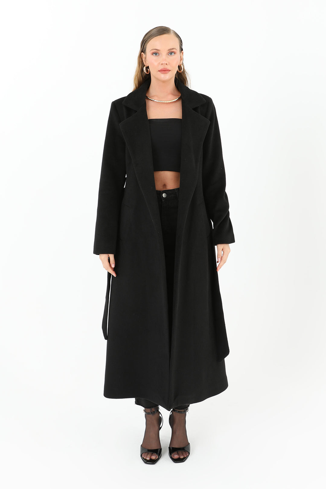 Woman wearing a long black coat on a white background