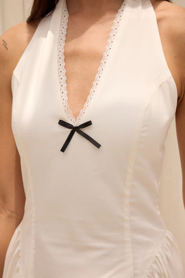 White sleeveless top with a black bow detail on a neutral background