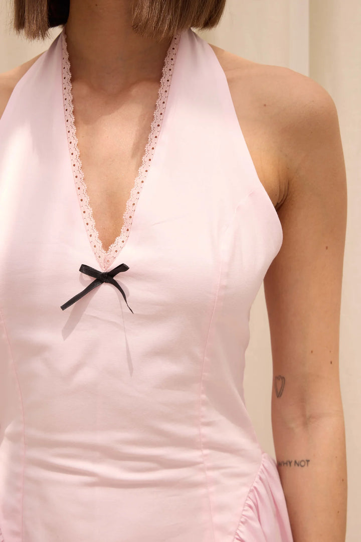 Light pink halter neck dress with lace trim and a black bow detail.