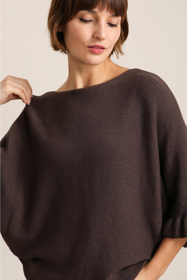 Woman wearing a brown sweater against a neutral background