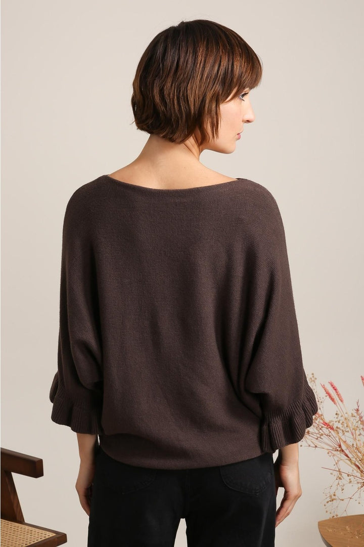 Woman wearing a brown sweater with a neutral background