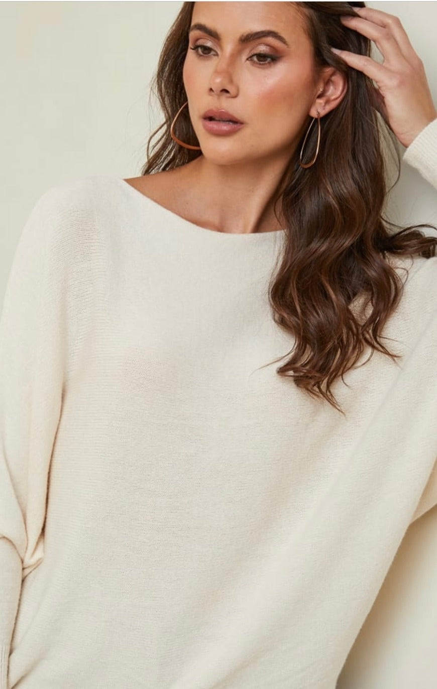 Woman wearing a beige sweater with a plain background