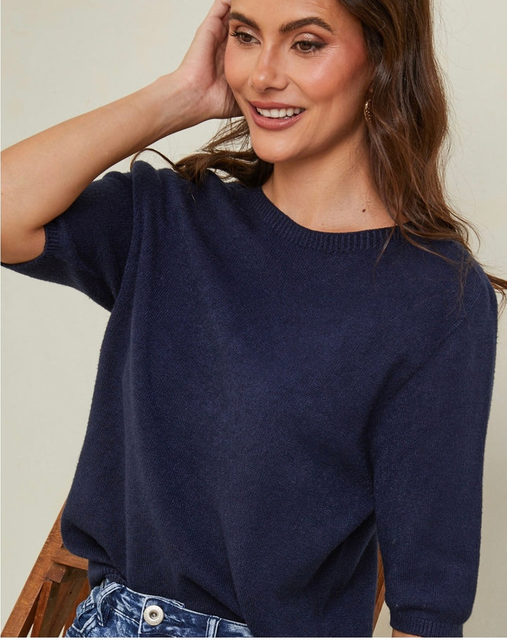 Woman wearing a navy blue sweater against a neutral background