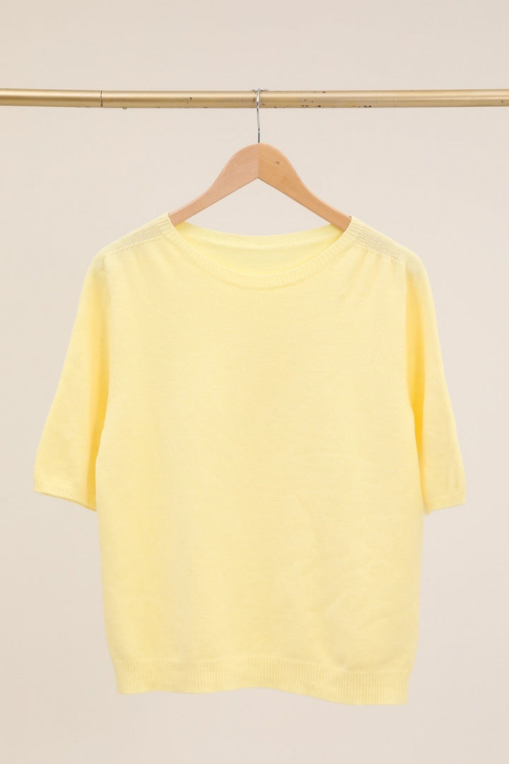 Yellow shirt on a hanger against a beige background