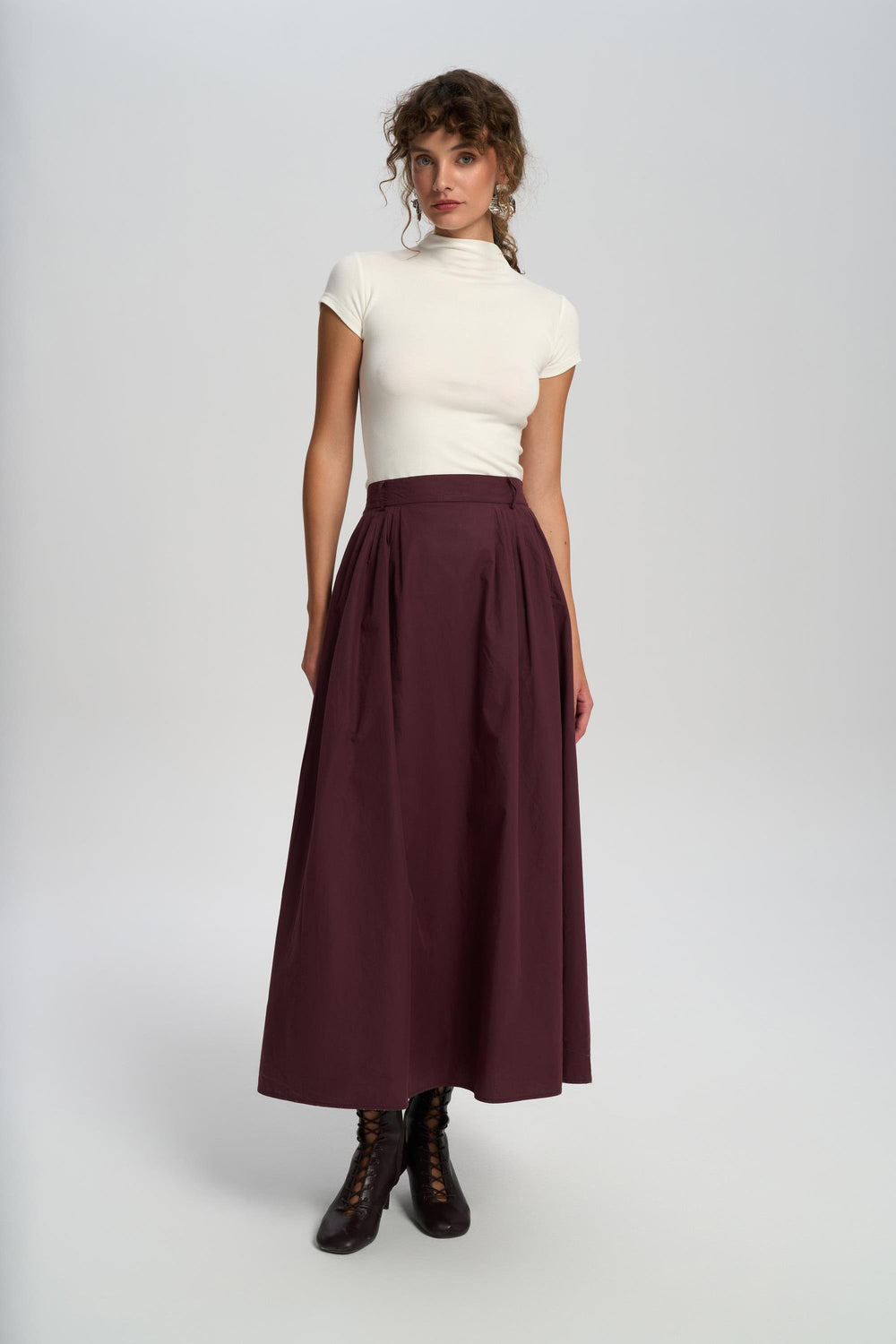 Woman wearing a white top and burgundy skirt on a white background