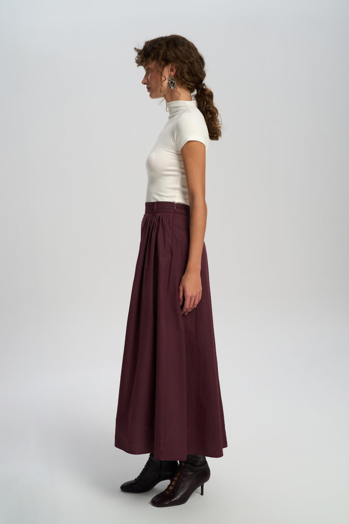 Woman wearing a white top and burgundy skirt on a white background