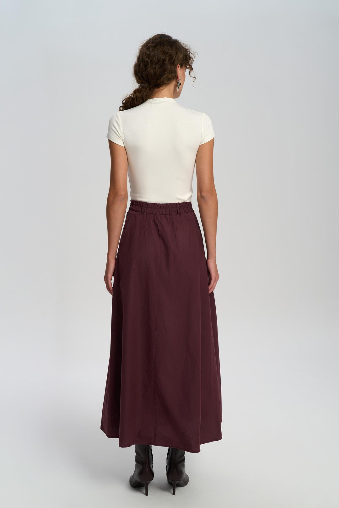 Woman wearing a white top and burgundy skirt on a white background