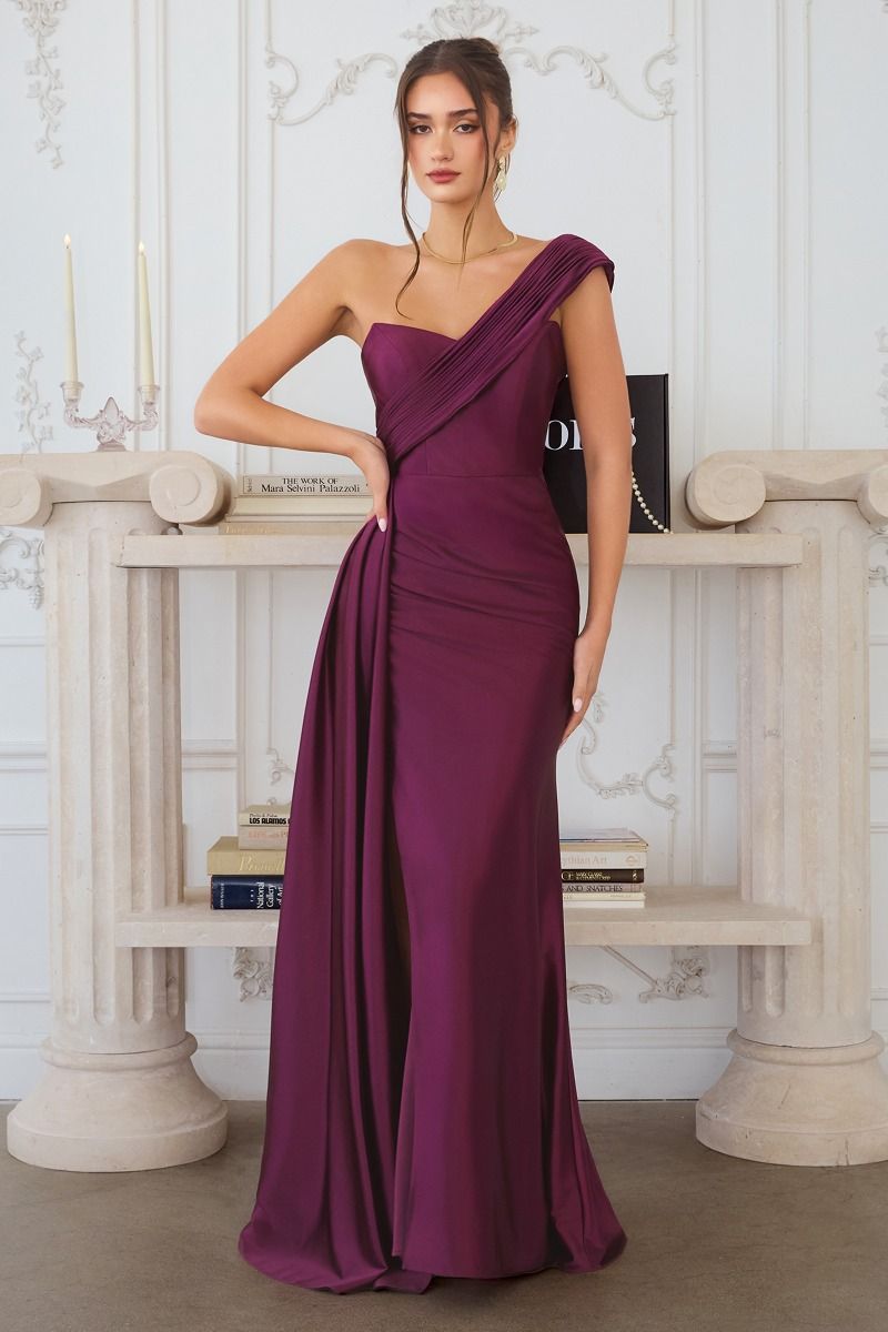 Woman wearing a purple one-shoulder dress in an elegant interior setting.