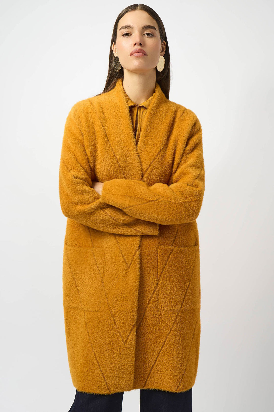 Woman wearing a mustard yellow textured coat on a white background