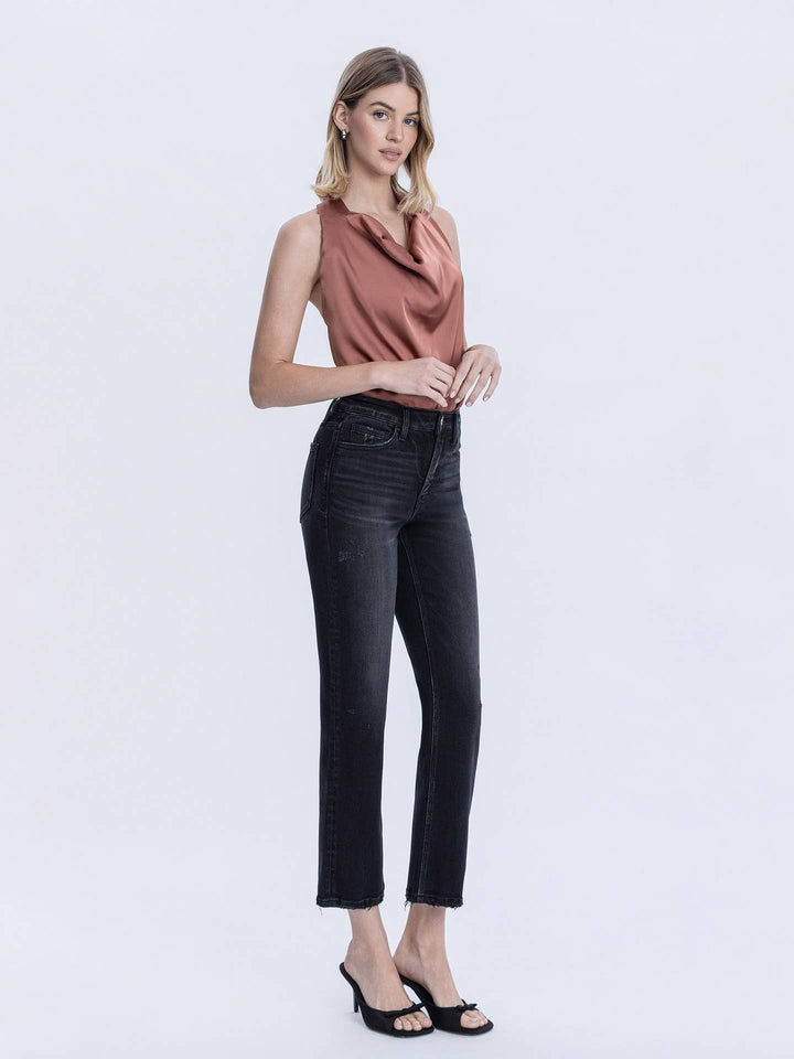 Woman wearing a sleeveless top and black jeans on a white background