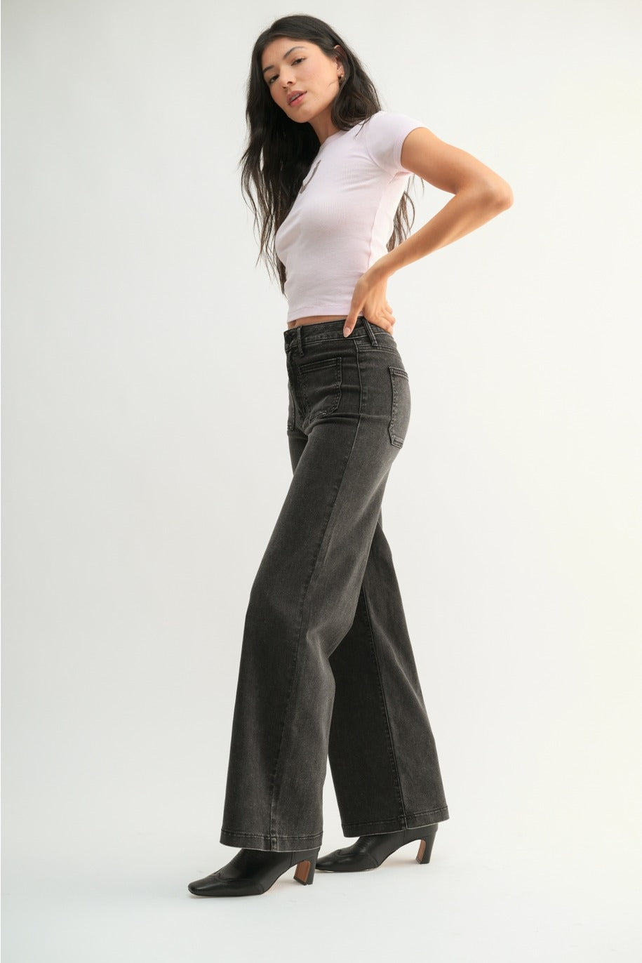 Woman wearing a white top and black wide-leg jeans on a white background