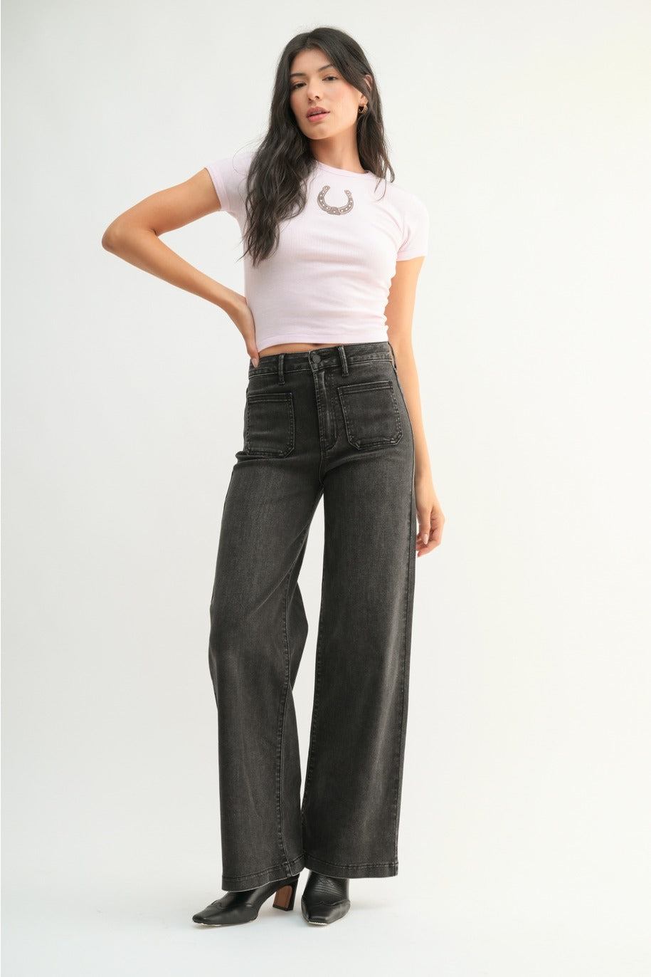 Woman wearing a white crop top and black wide-leg jeans on a white background
