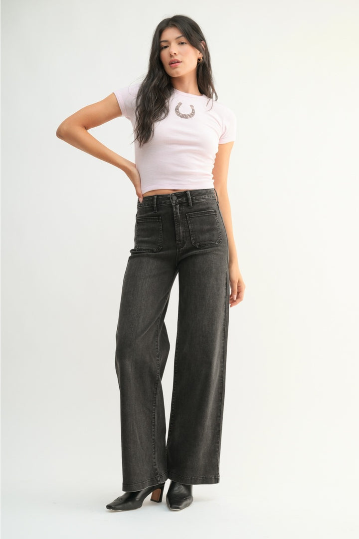 Woman wearing a white crop top and black wide-leg jeans on a white background