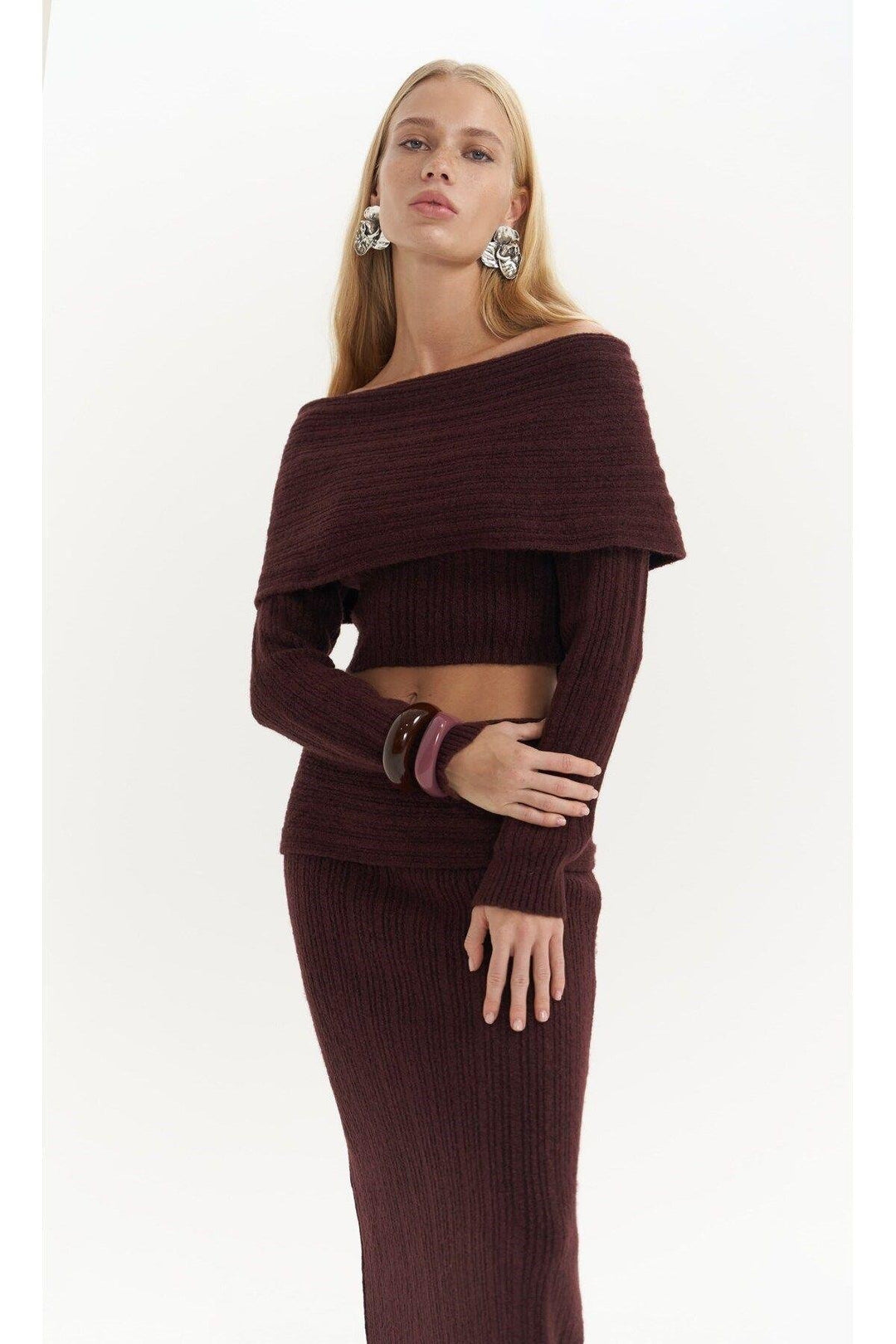 Woman wearing a burgundy ribbed outfit on a white background