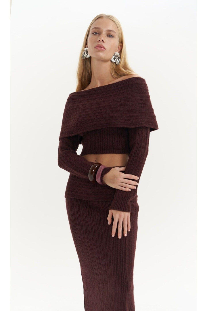 Woman wearing a burgundy ribbed outfit on a white background