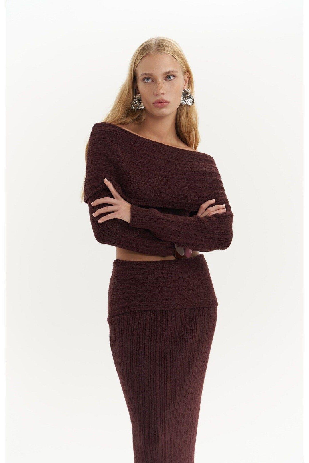 Woman wearing a brown ribbed sweater and skirt set on a white background