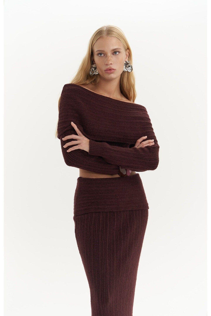 Woman wearing a brown ribbed sweater and skirt set on a white background