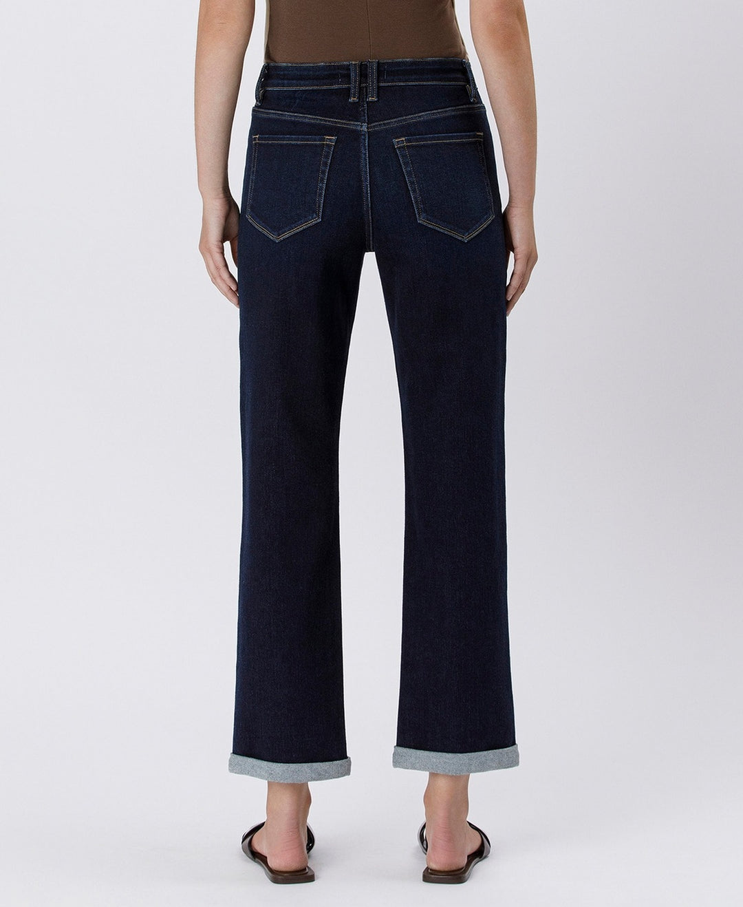 Dark blue jeans worn by a person on a white background