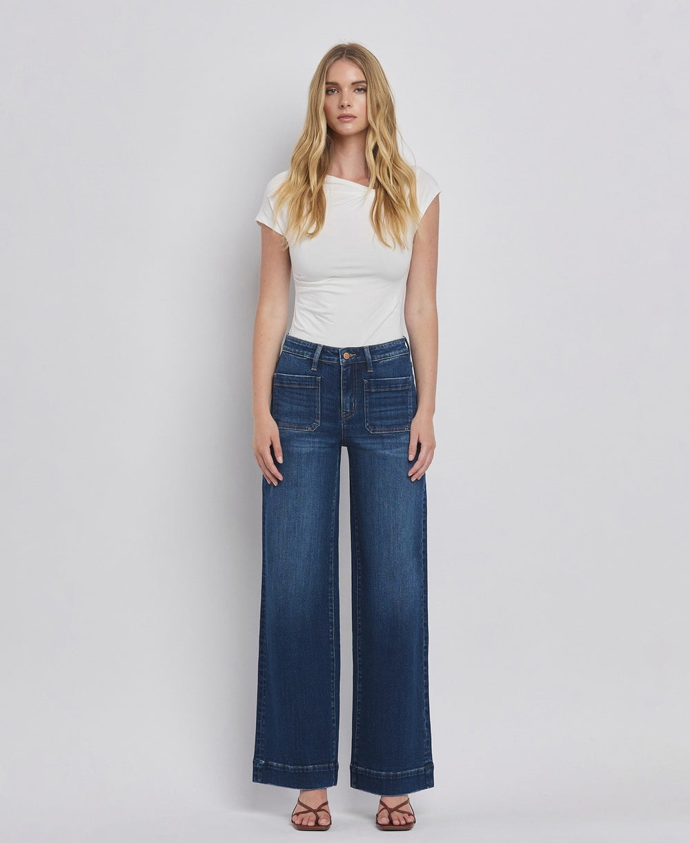 Woman wearing a white top and blue jeans on a plain background
