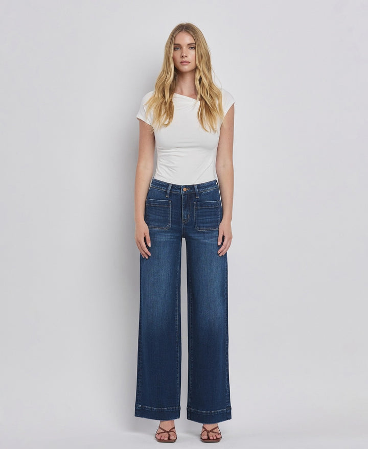 Woman wearing a white top and blue jeans on a plain background