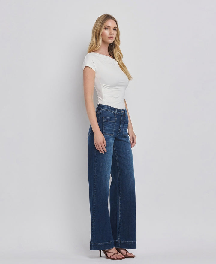 Woman wearing a white top and blue jeans on a plain background
