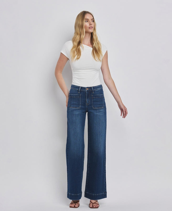 Woman wearing a white top and blue jeans on a plain background