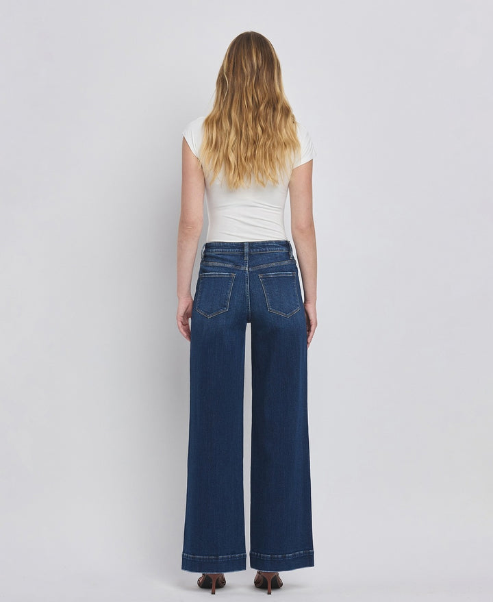 Person wearing blue jeans and a white top on a plain background