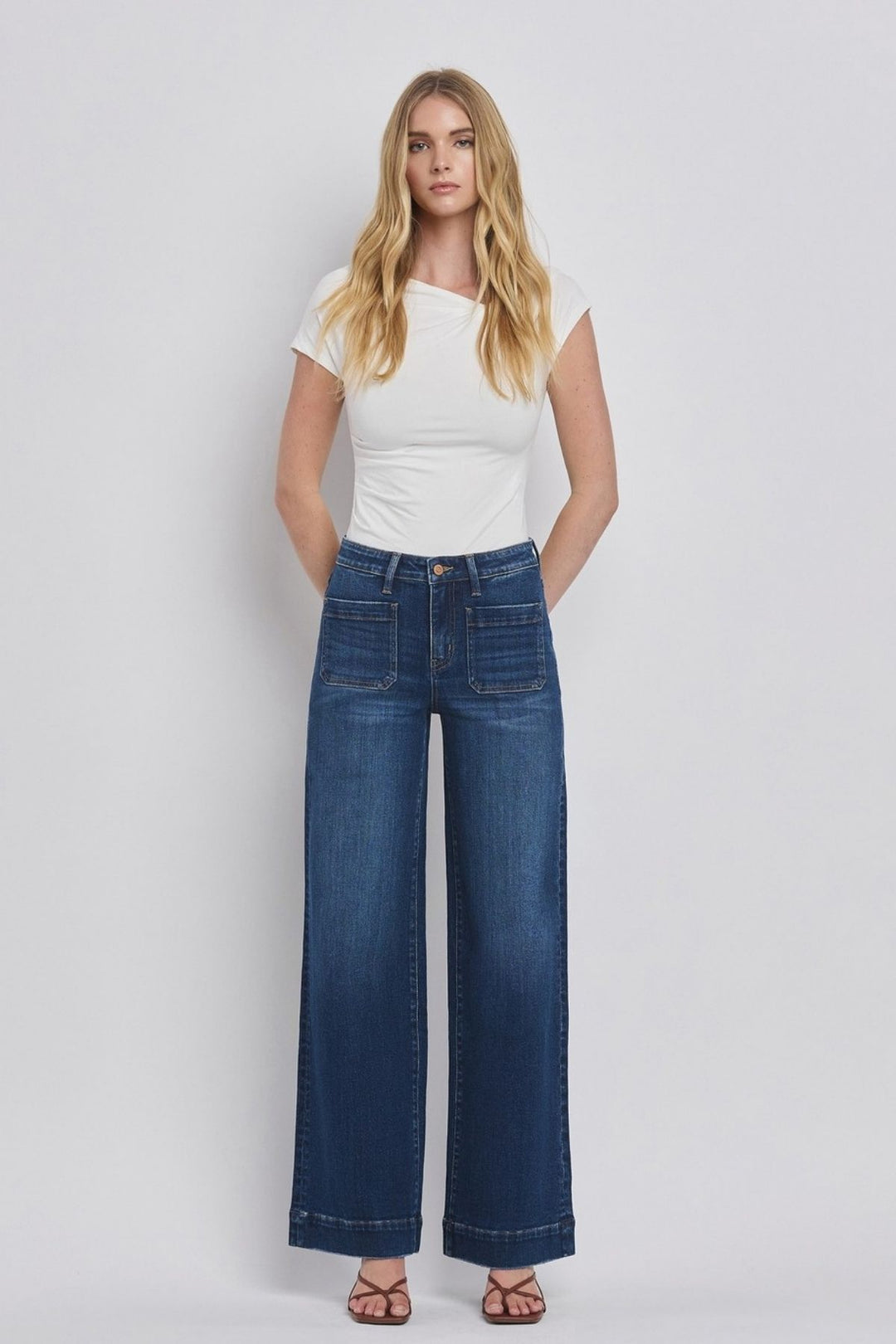 Woman wearing a white t-shirt and blue jeans on a plain background