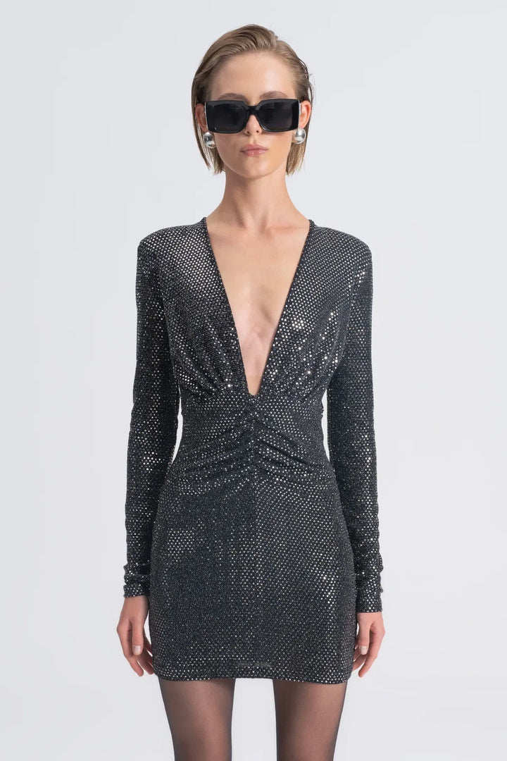 Woman wearing a black sequin dress with long sleeves on a white background