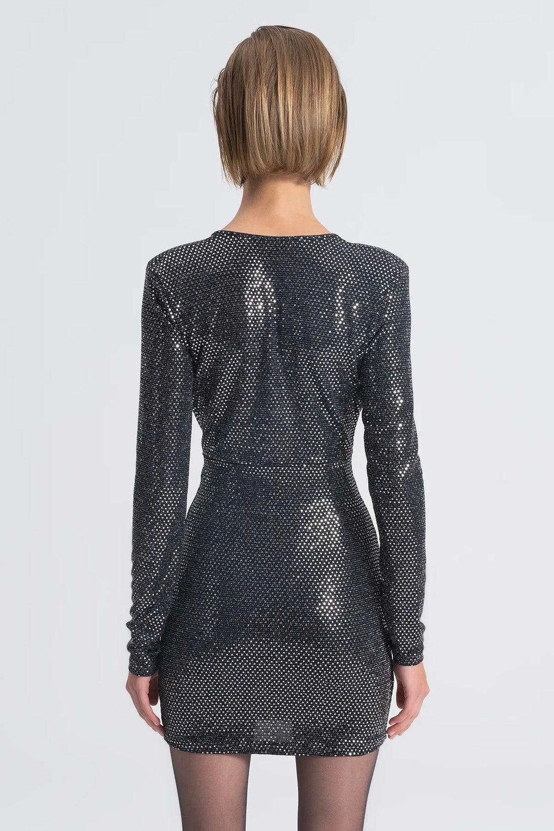 Black sequin dress worn by a model on a white background