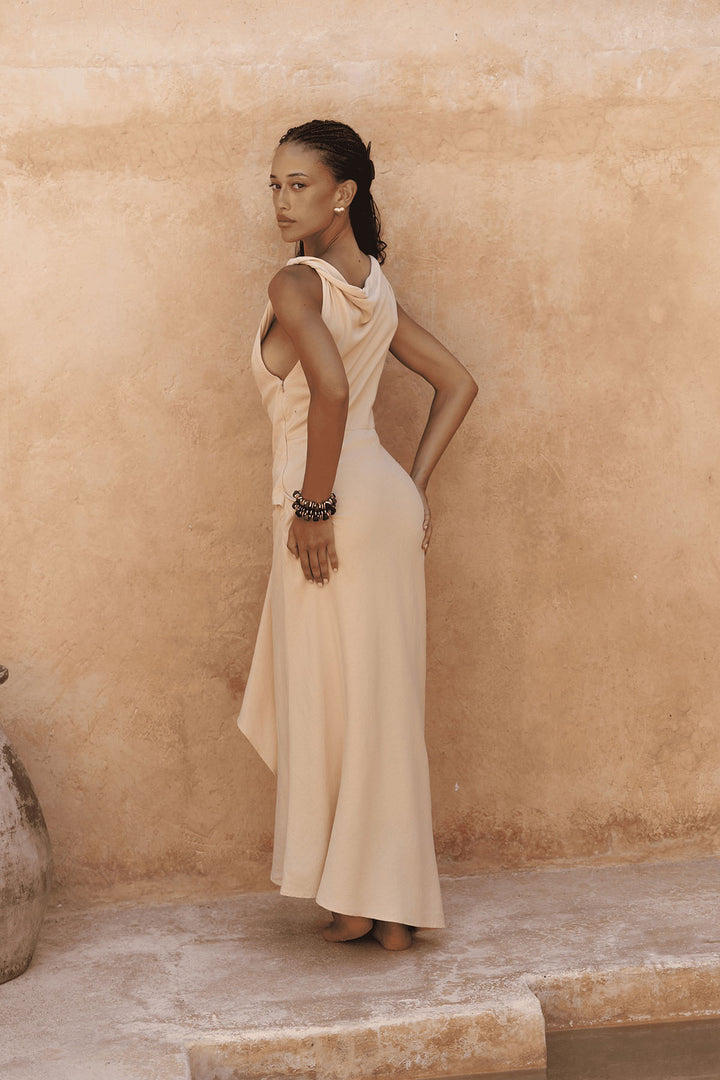 Woman in a beige dress standing against a beige wall