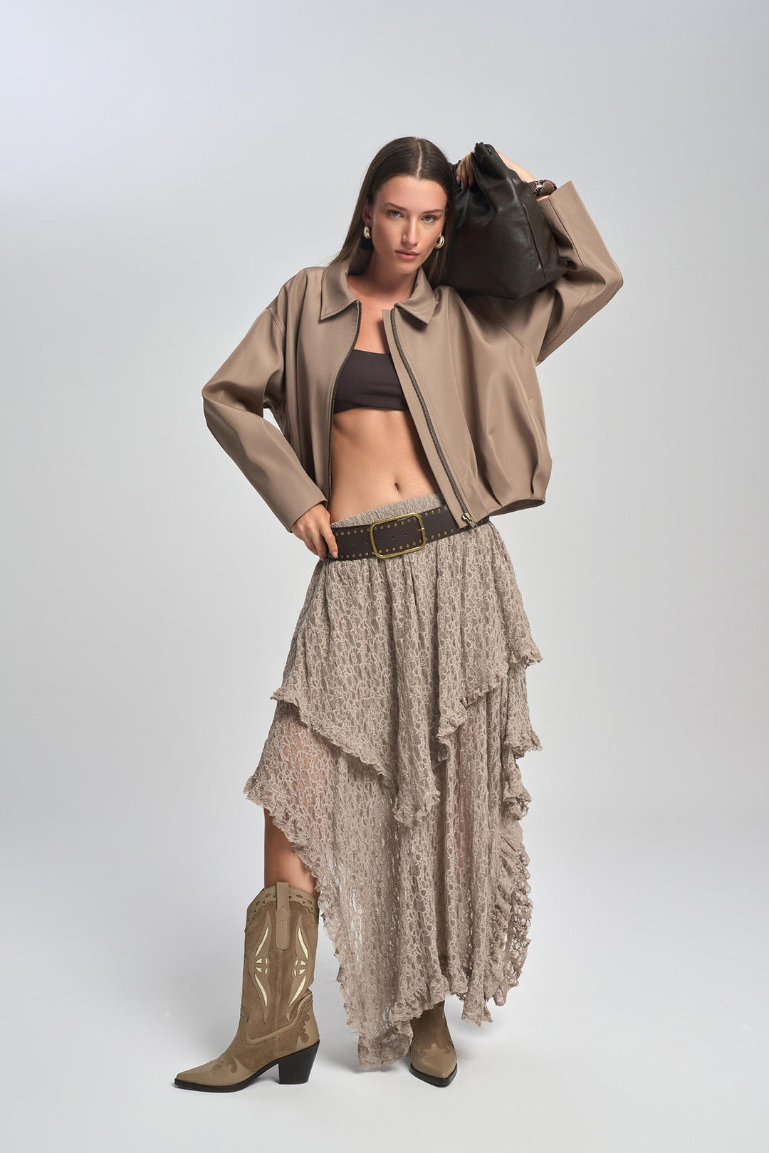 Woman wearing a beige jacket, skirt, and boots on a white background