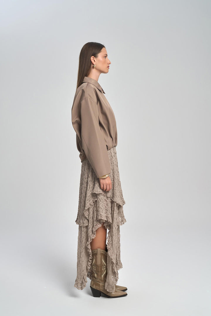 Woman wearing a beige shirt and skirt with brown boots on a white background