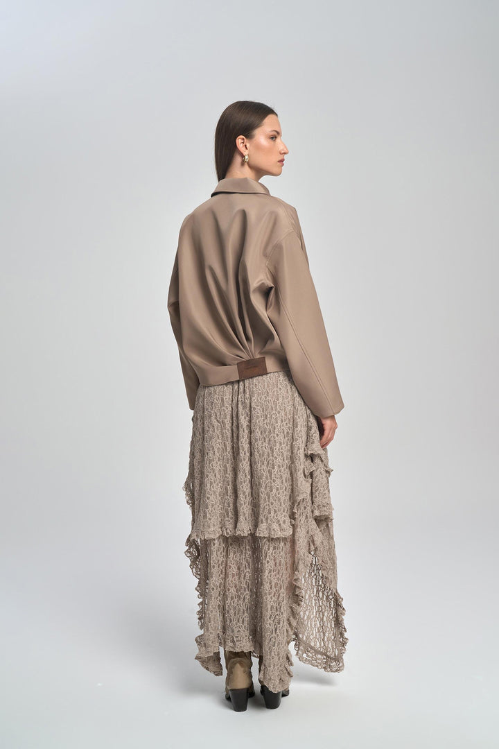 Woman wearing a beige jacket and patterned skirt on a white background