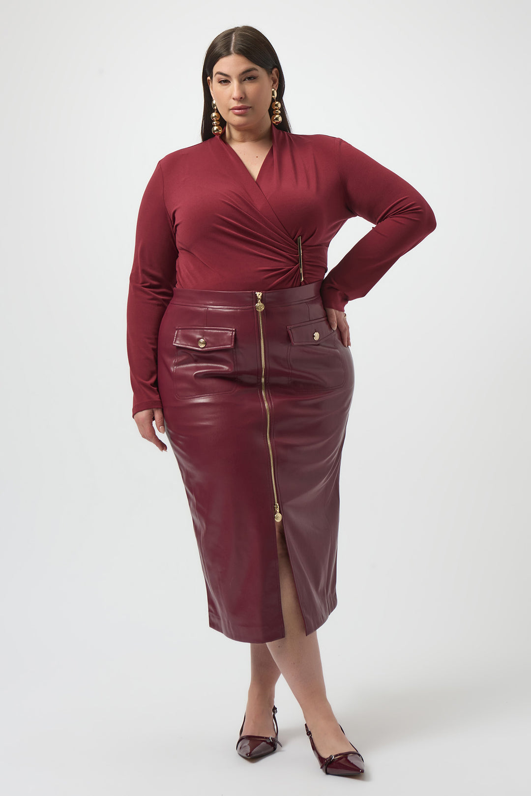 Woman wearing a burgundy dress with a leather skirt on a white background