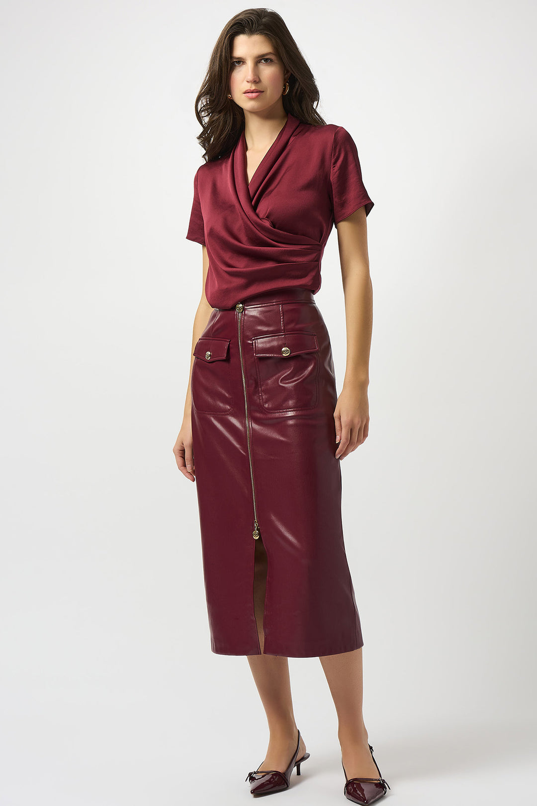 Woman wearing a burgundy top and leather skirt on a white background