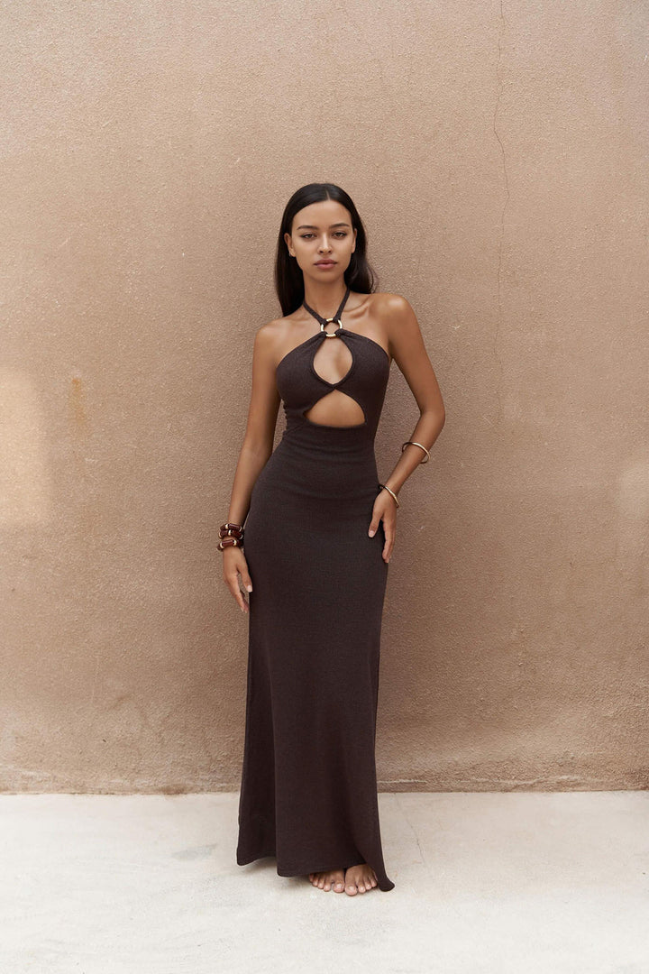 Woman wearing a long black dress against a beige wall