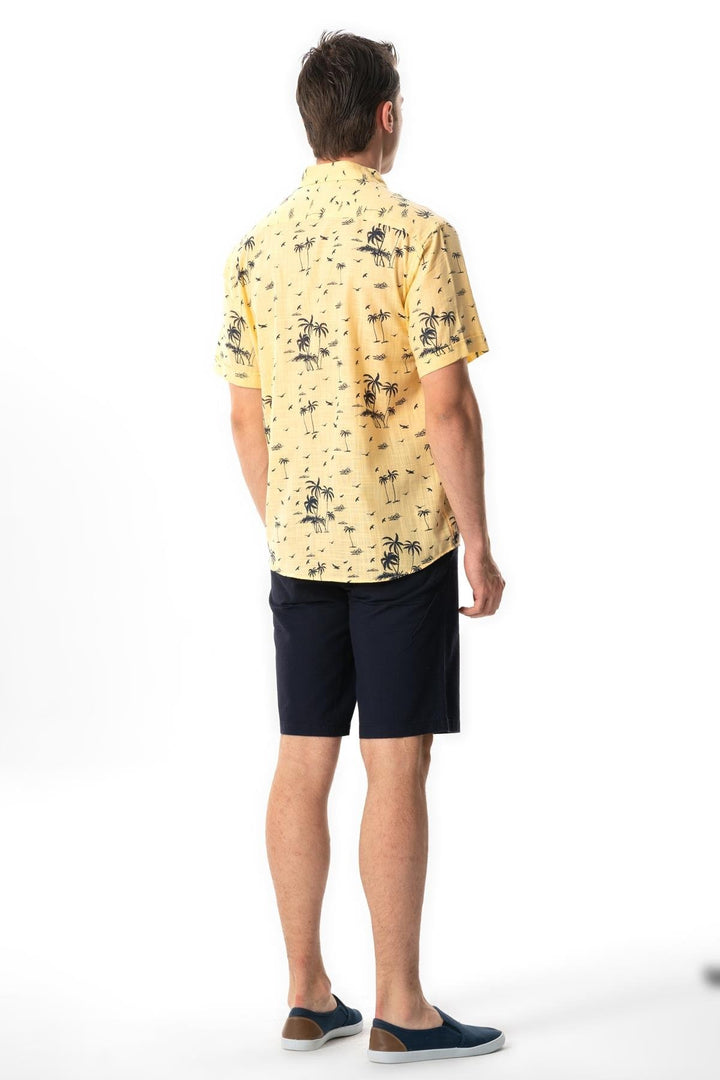Person wearing a yellow patterned shirt and navy shorts on a white background