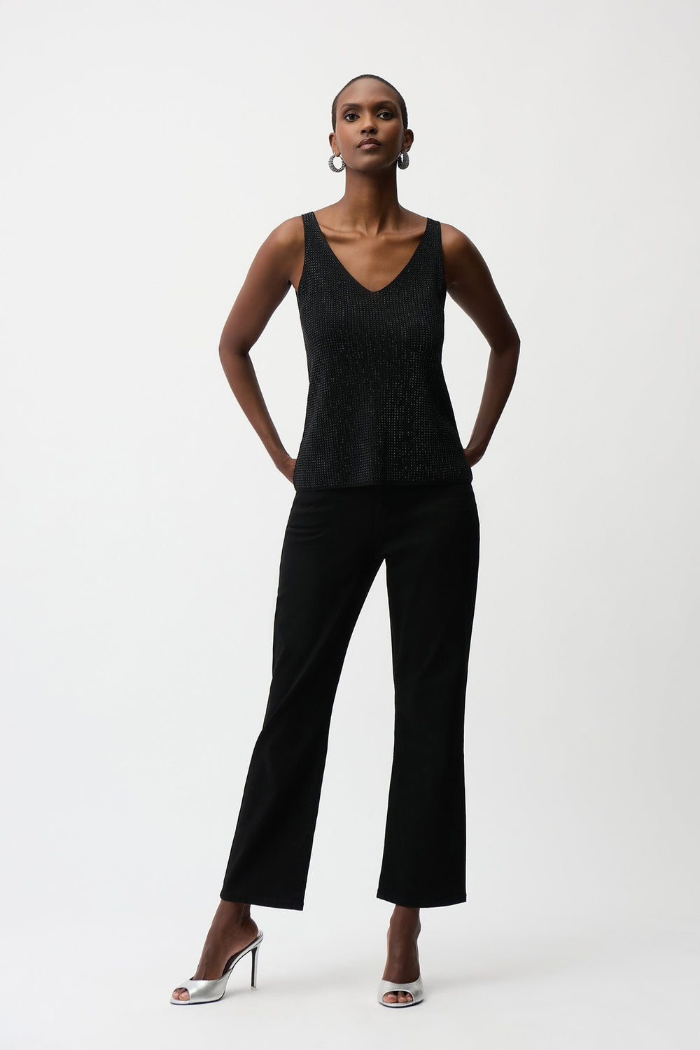 Woman wearing a black sleeveless top and black pants on a white background