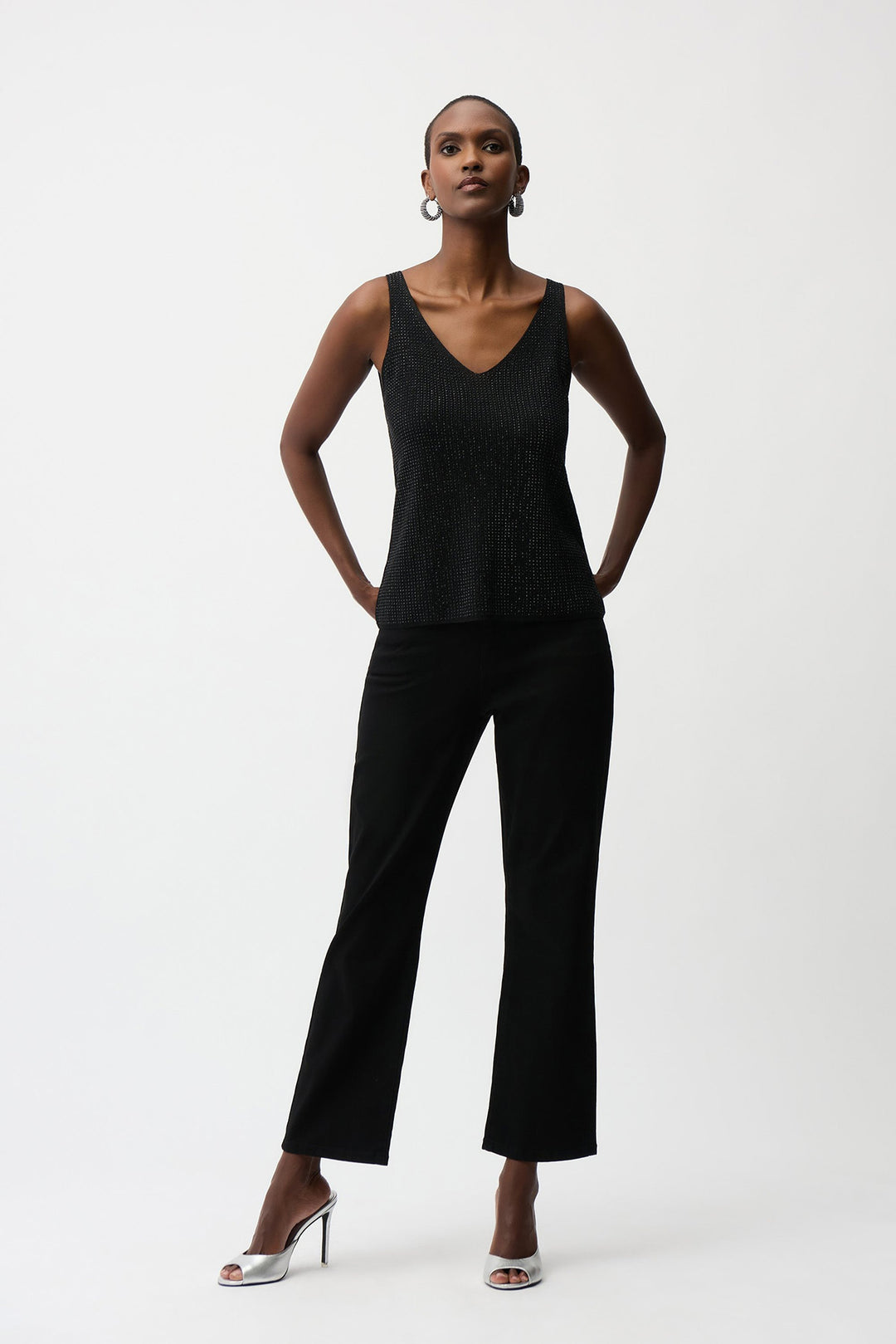 Woman wearing a black sleeveless top and black pants on a white background