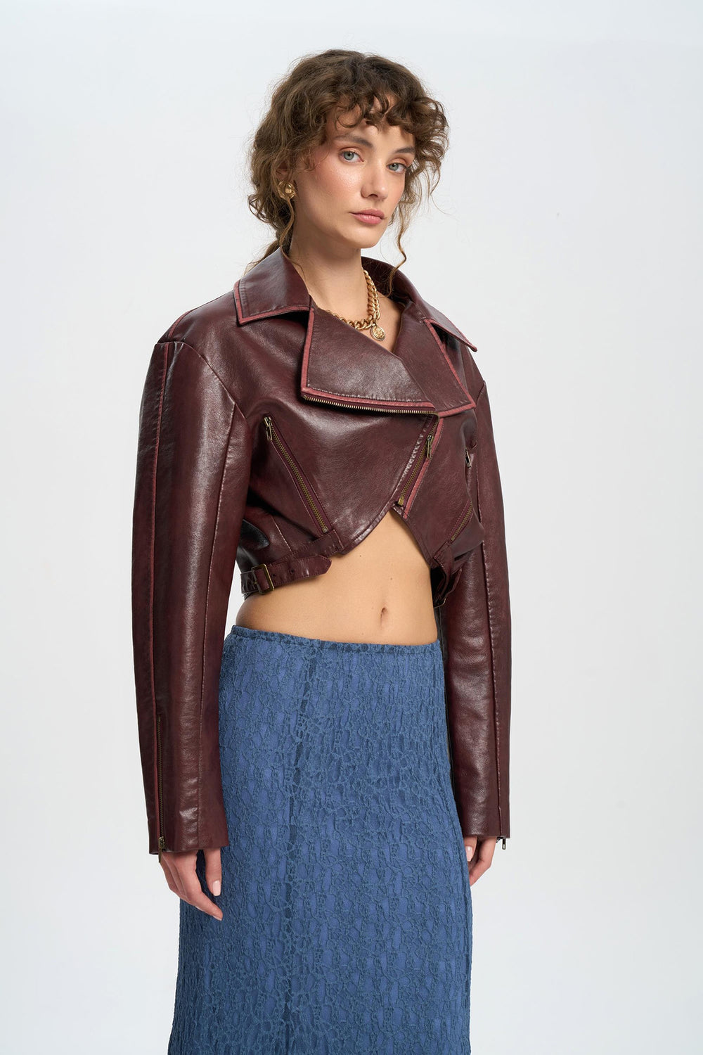 Woman wearing a brown leather jacket and blue skirt on a white background