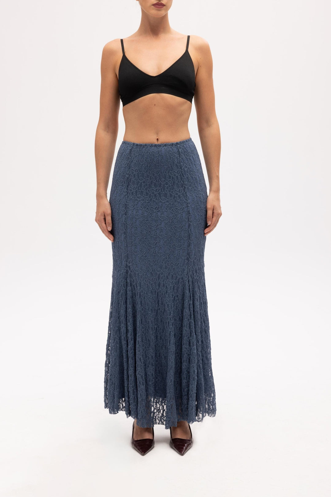 Woman wearing a black top and blue lace skirt on a white background
