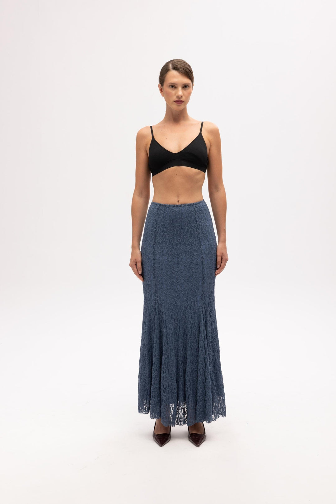 Woman wearing a black top and blue denim skirt on a white background