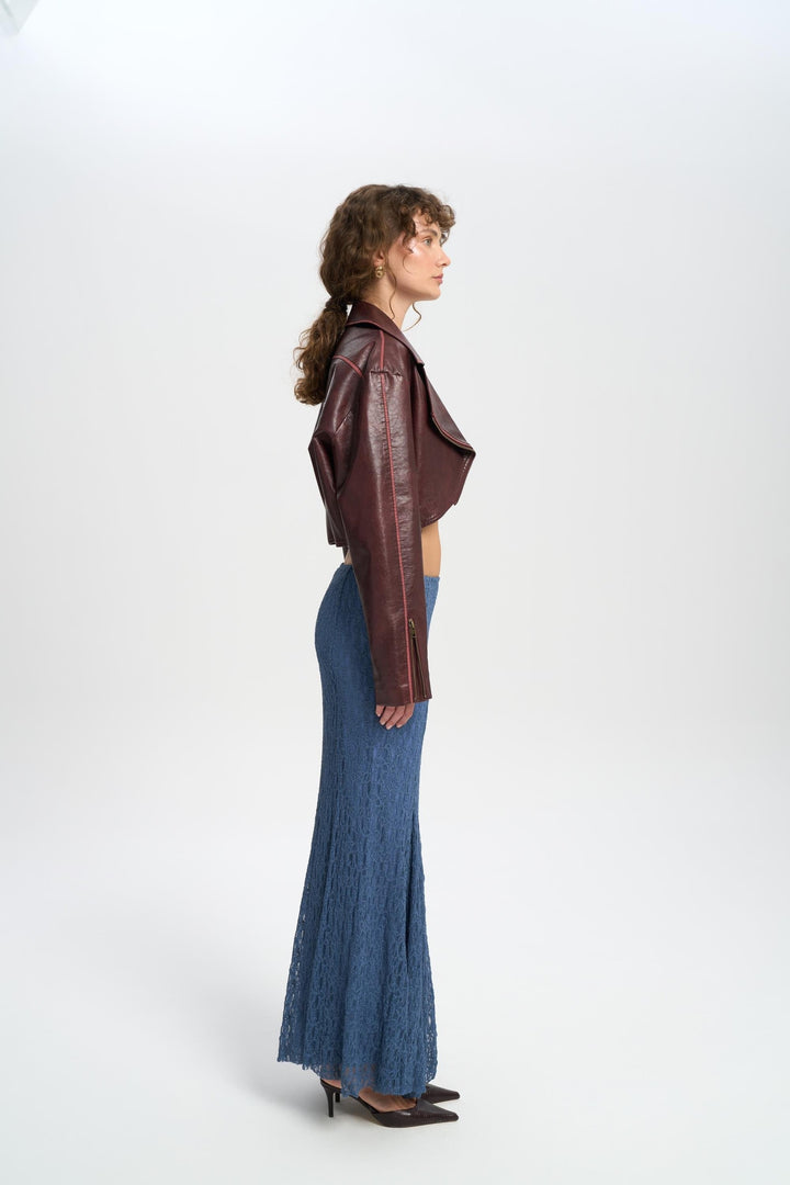 Woman wearing a brown leather jacket and blue denim pants on a white background