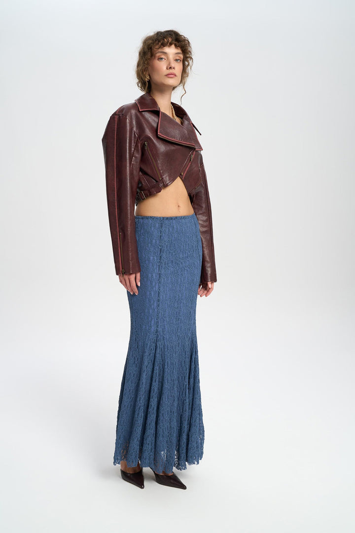 Woman wearing a brown leather jacket and blue denim skirt on a white background