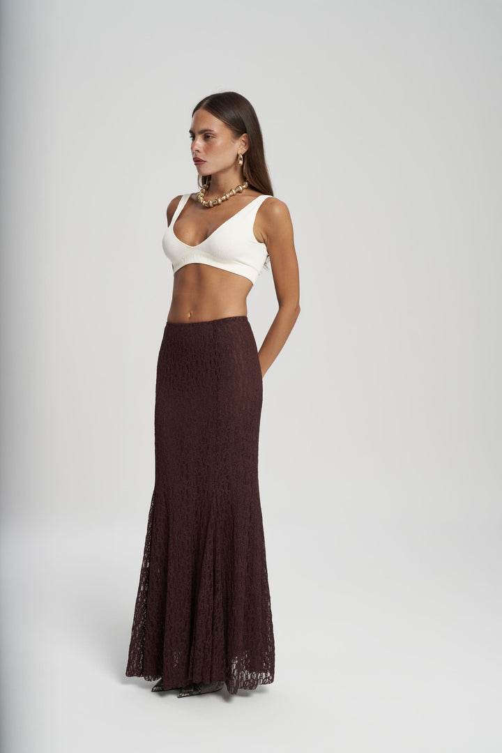 Woman wearing a white top and brown skirt on a white background