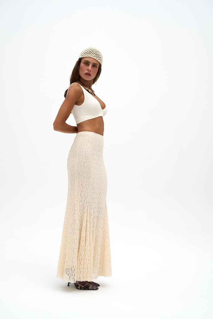 Woman wearing a white top and long beige skirt on a white background