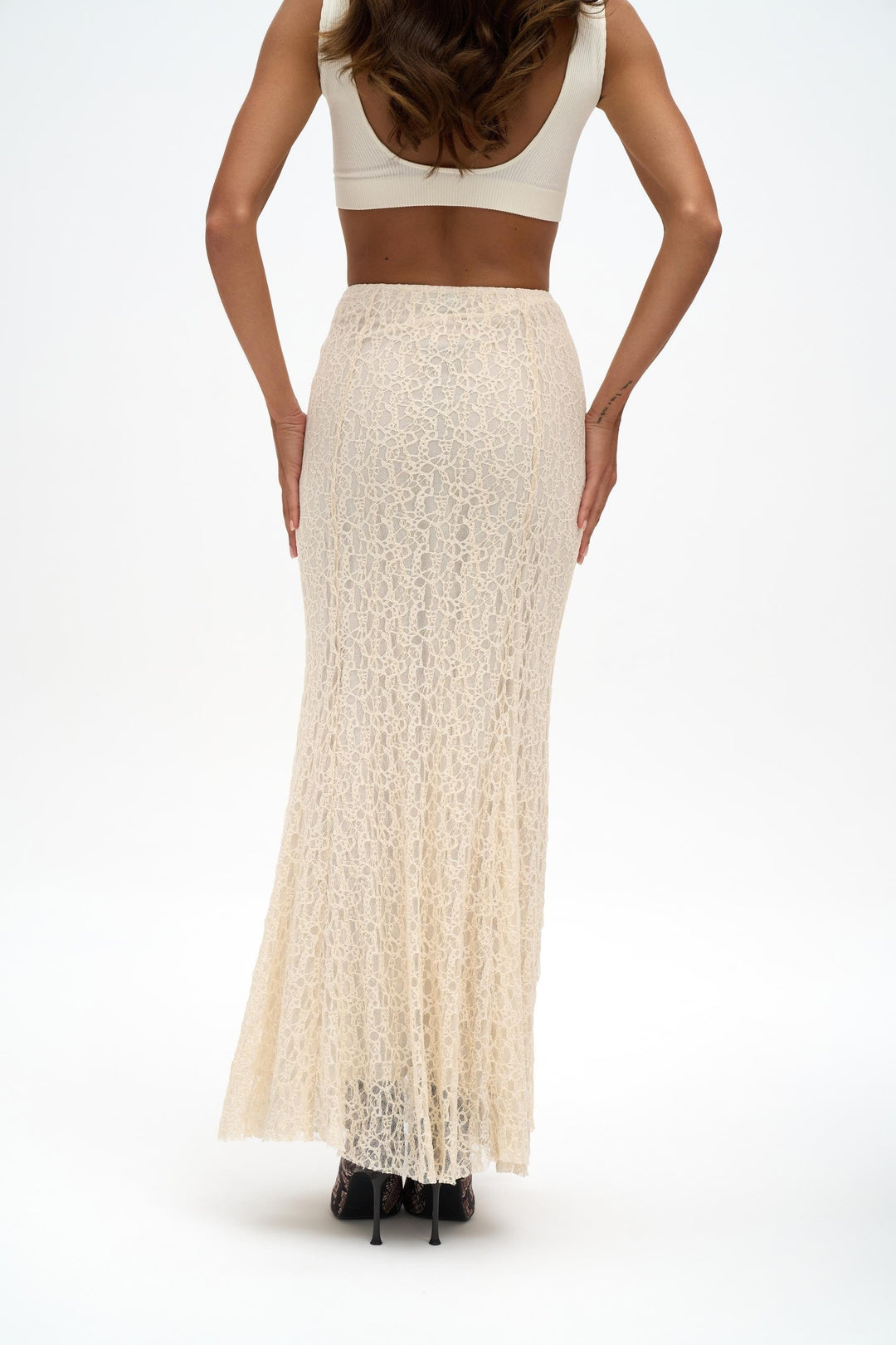 Woman wearing a white lace skirt and crop top on a white background
