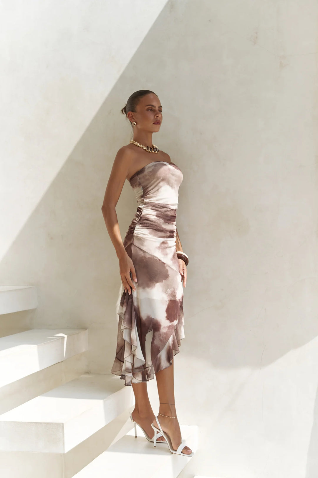 Woman in a strapless dress standing on a white staircase